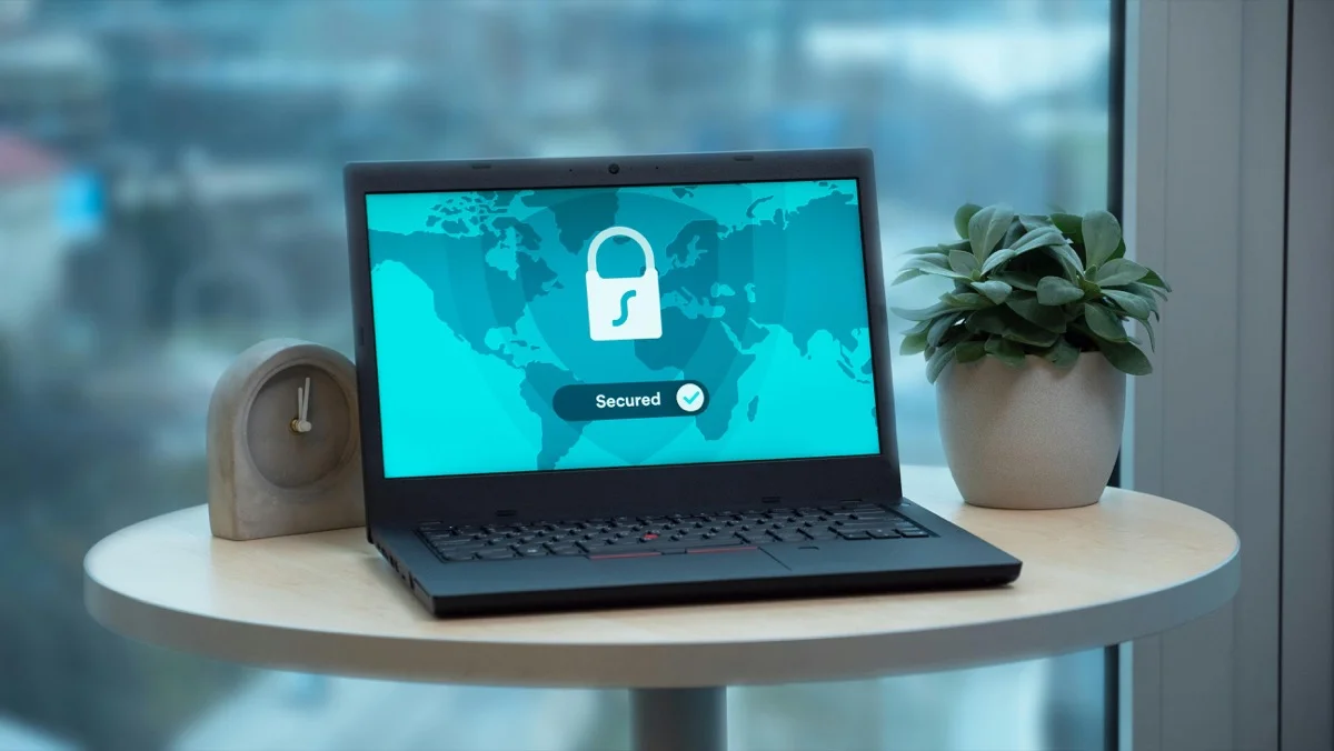 Laptop with security lock symbol on a table next to a plant